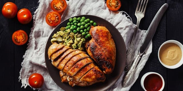 Plate of broiled chicken and vegetables to illustrate the question, "How much protein can the body absorb at once?"
