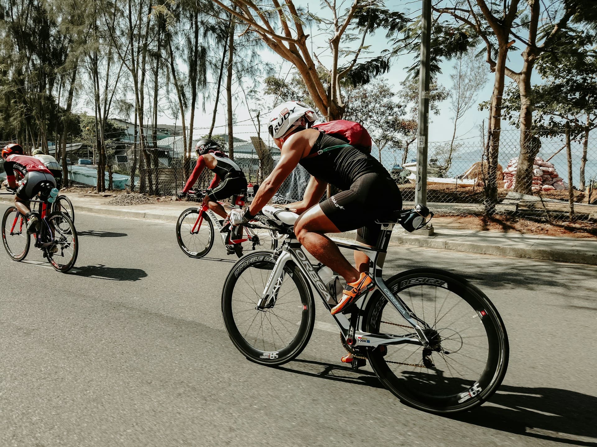triathlete kit - three men bicycle up a hill in a triathalon 