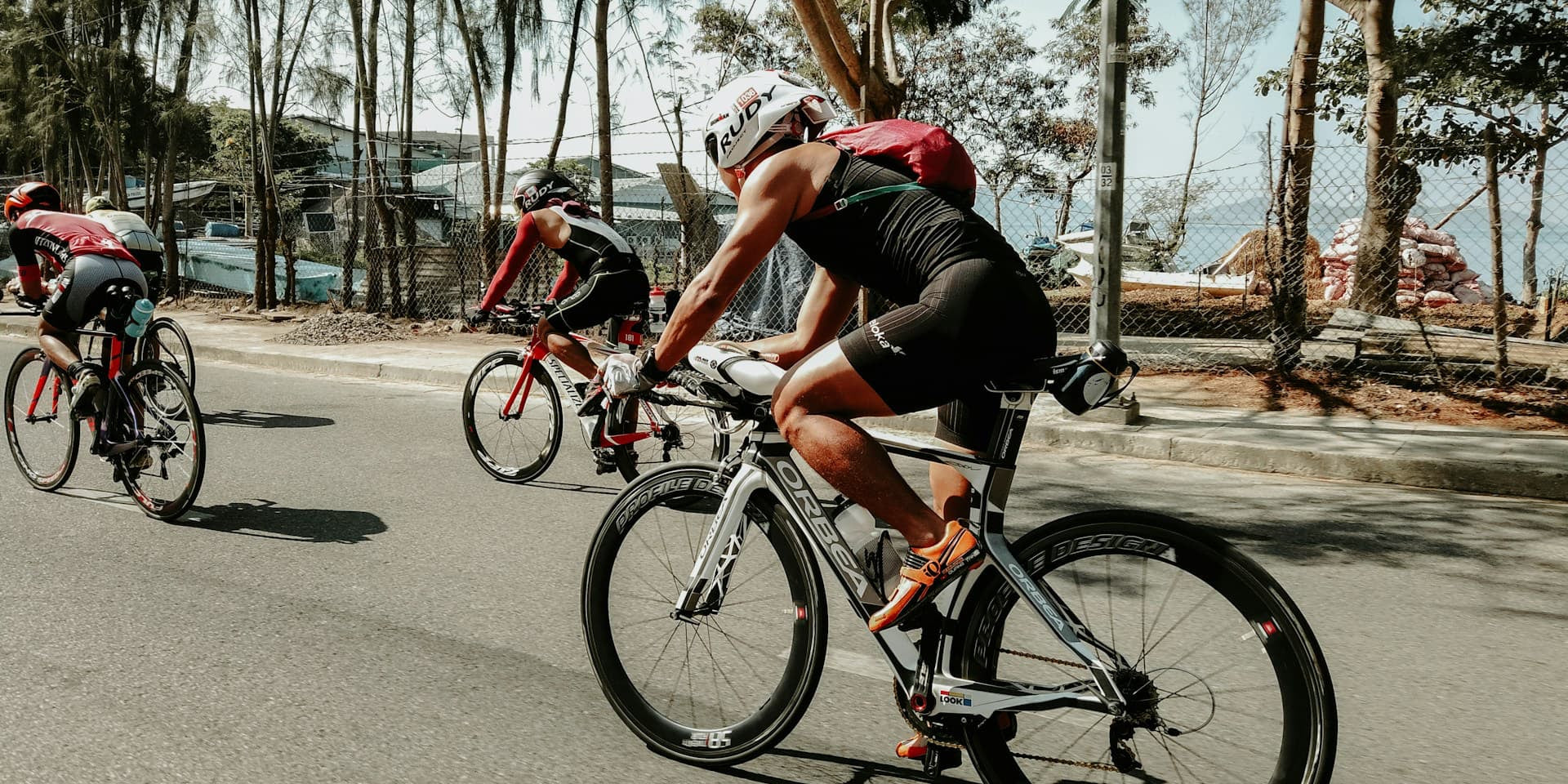 triathlete kit - three men bicycle up a hill in a triathalon 