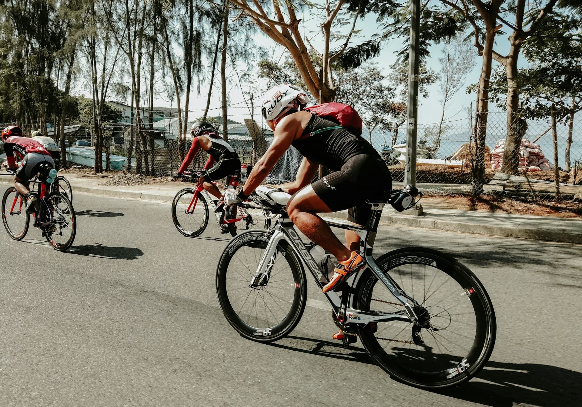 triathlete kit - three men bicycle up a hill in a triathalon 