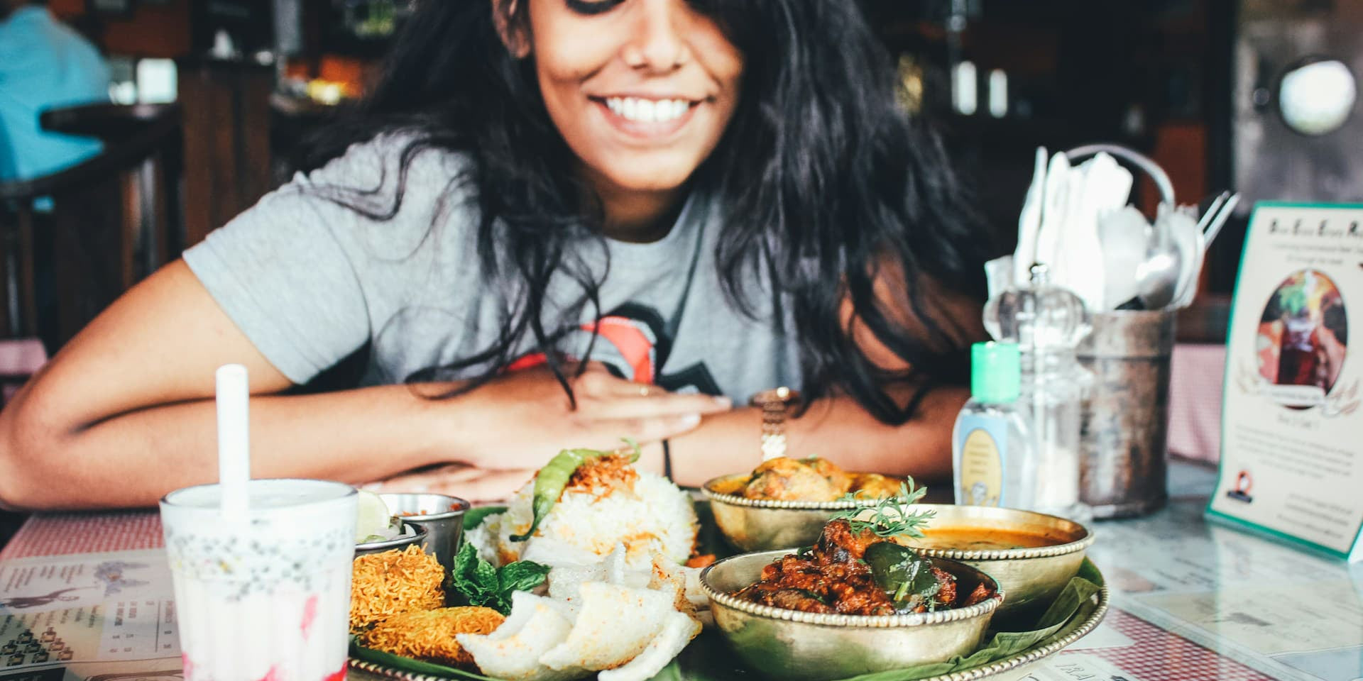 What Is a kcal vs Calorie? Woman wonders as she looks down at her meal and smiles 