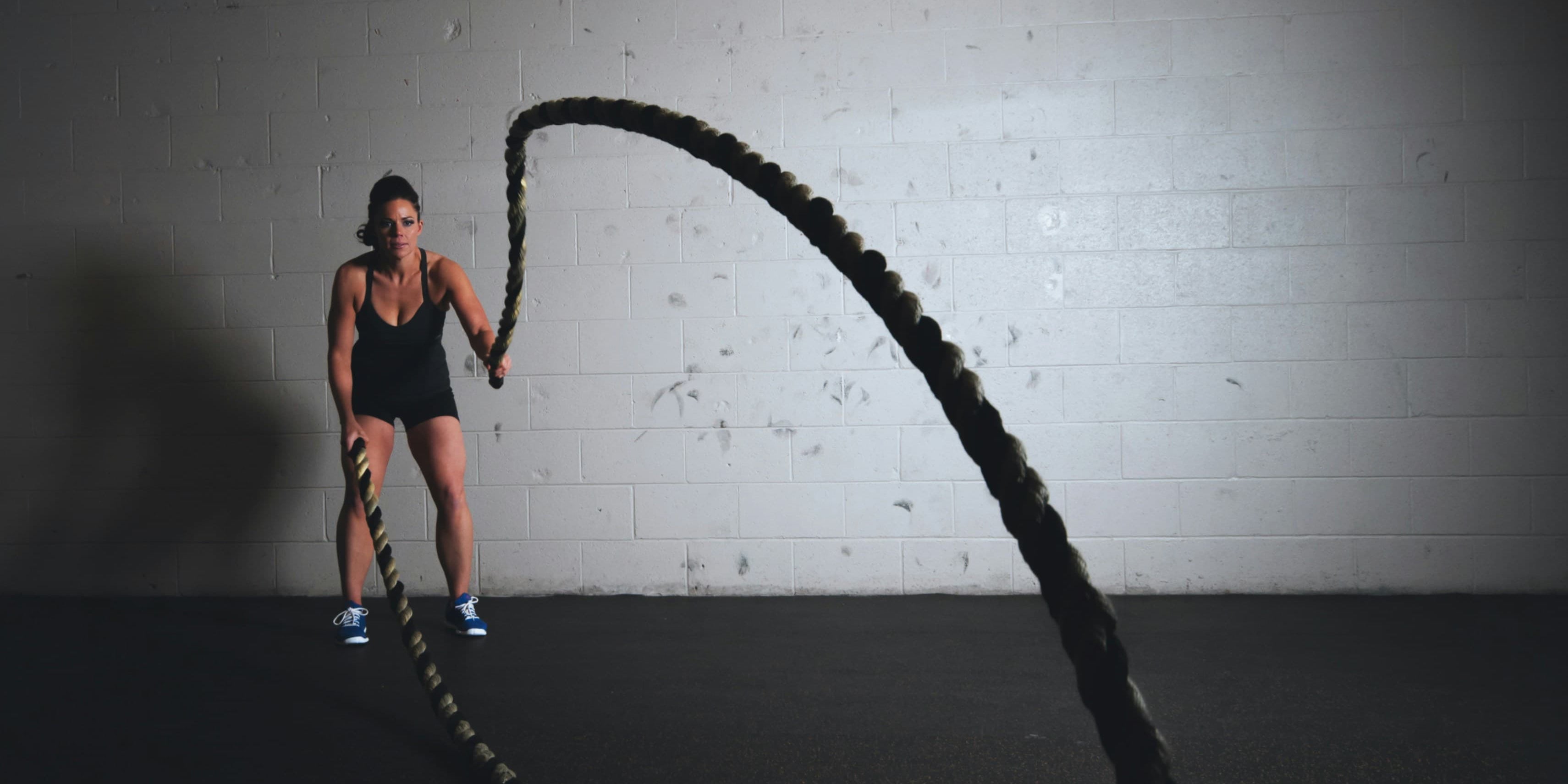 Woman who uses collagen and protein to stay fit, shown using battle ropes. 