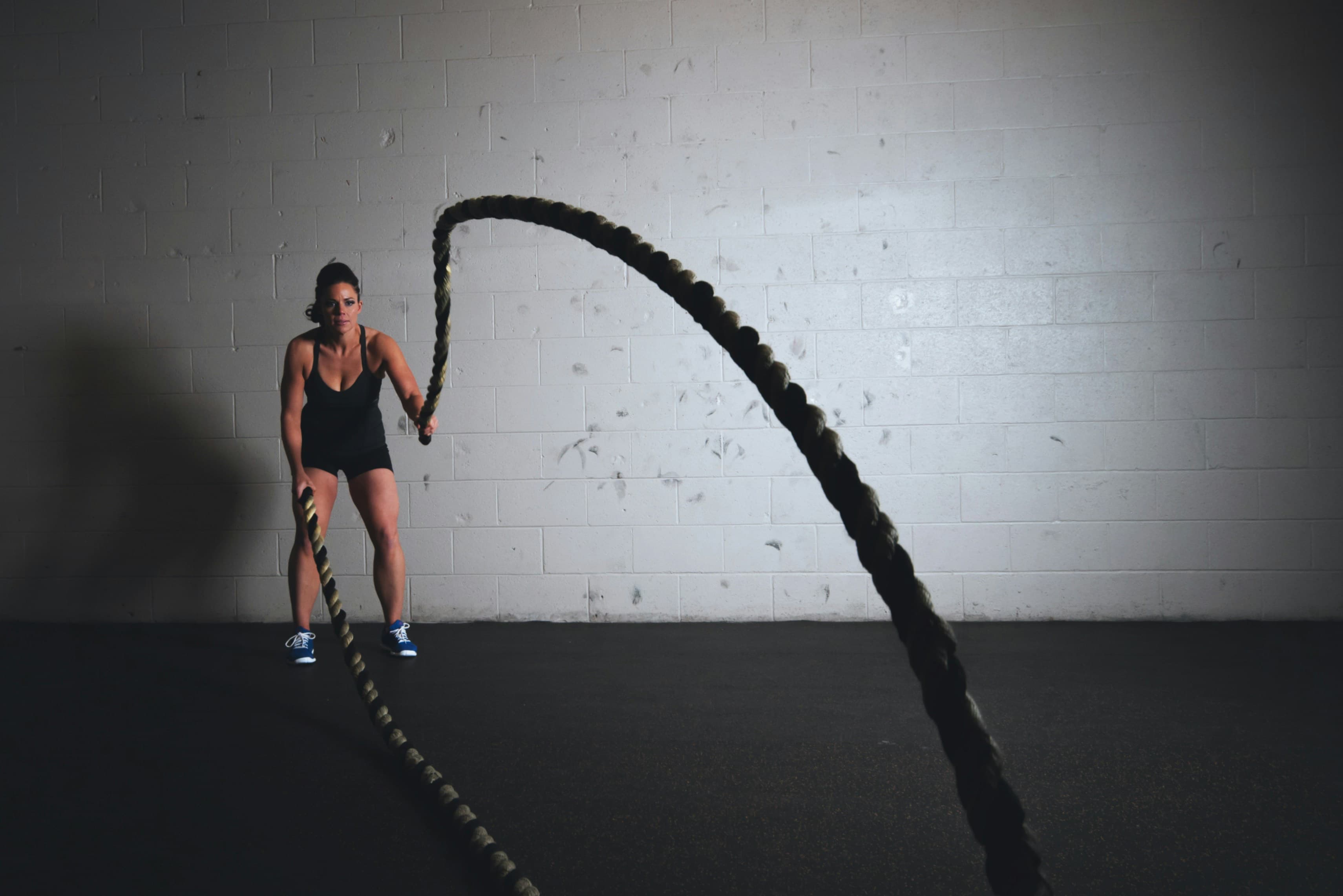Woman who uses collagen and protein to stay fit, shown using battle ropes. 