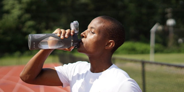 Man depicting a drink with the cleanest protein powder while standing on a track 