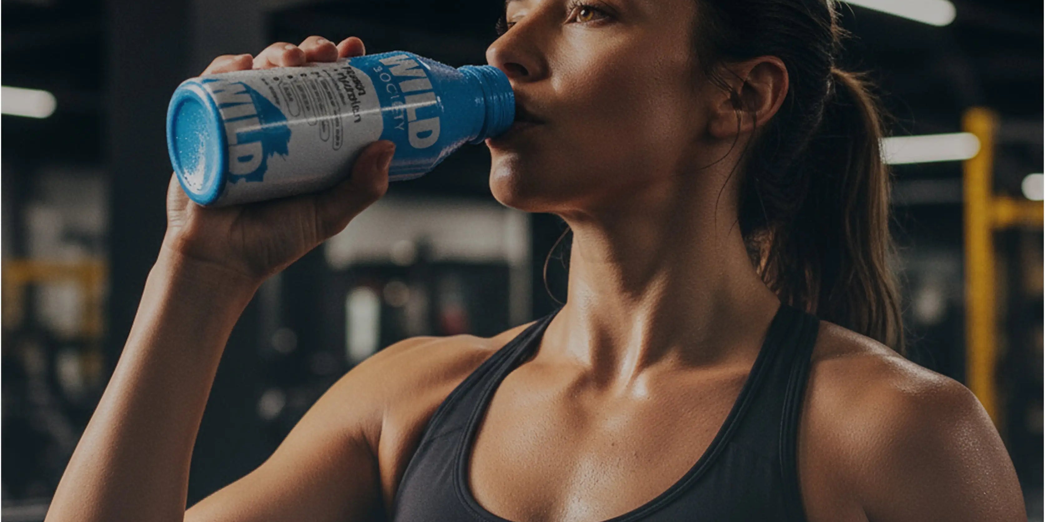 Woman drinking a Blue Razz Protein + Hydration bottle