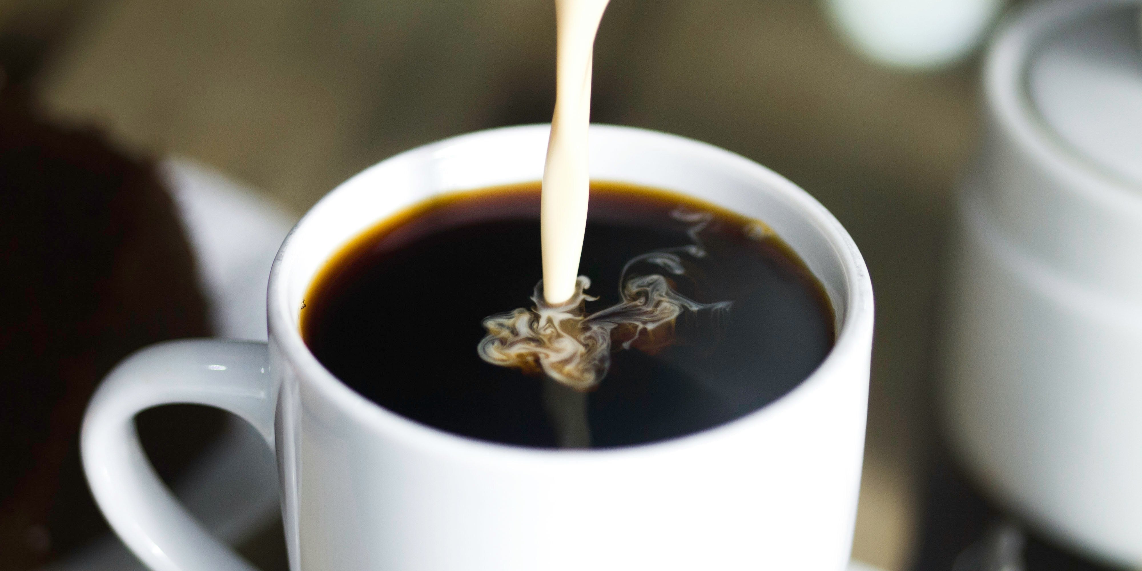 Milk pouring into a cup of coffee