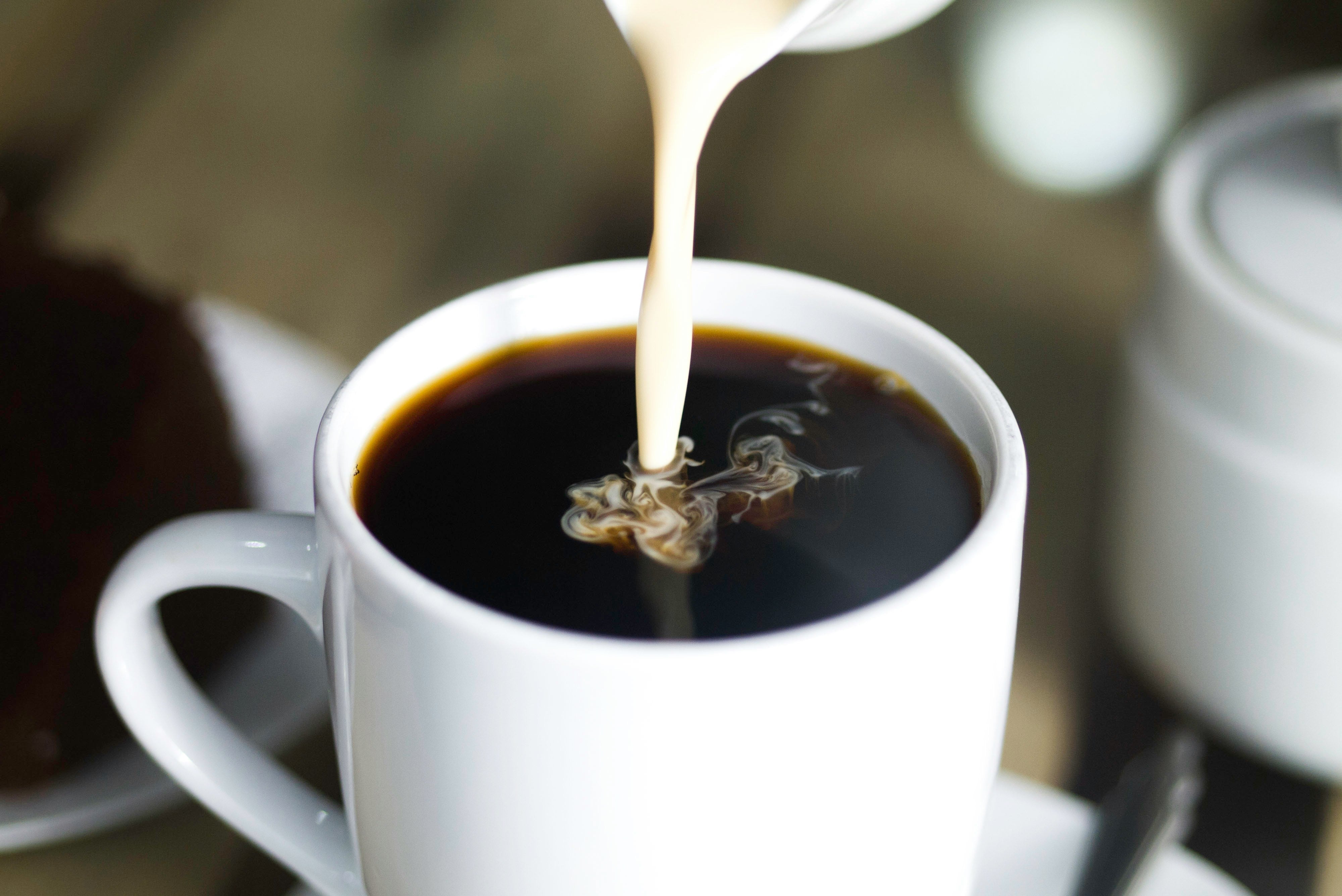 Milk pouring into a cup of coffee