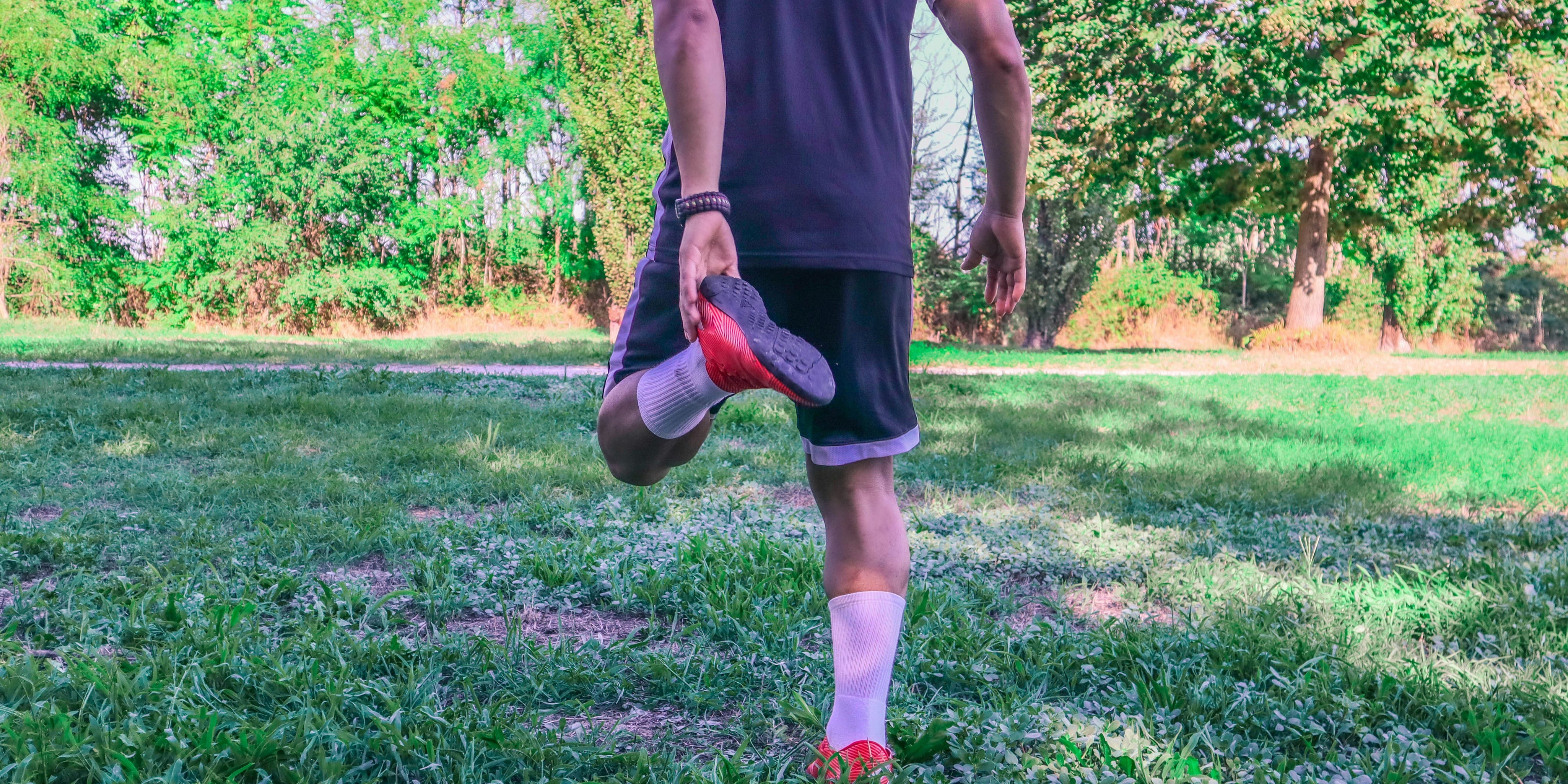 what helps sore muscles after workout? Man stretches post-workout in the grass