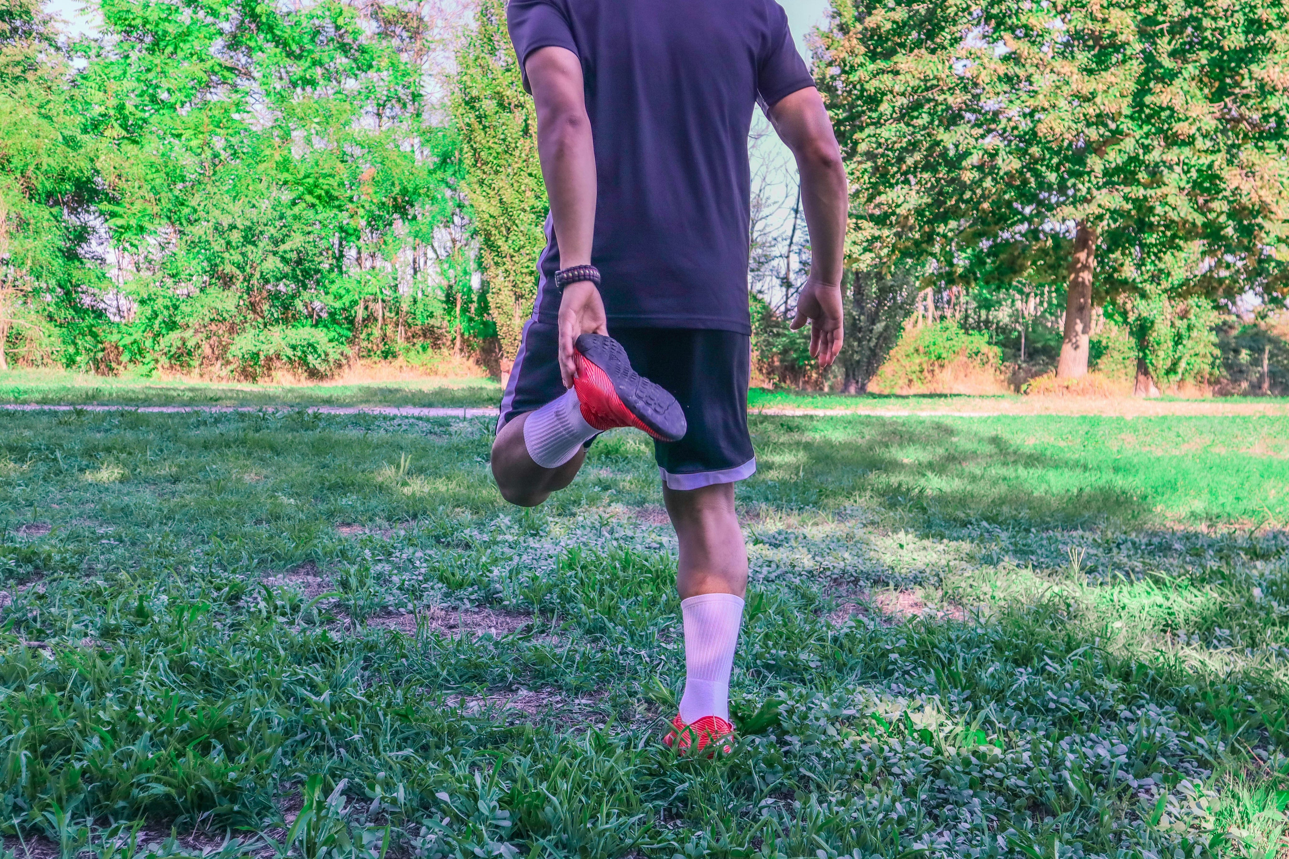 what helps sore muscles after workout? Man stretches post-workout in the grass