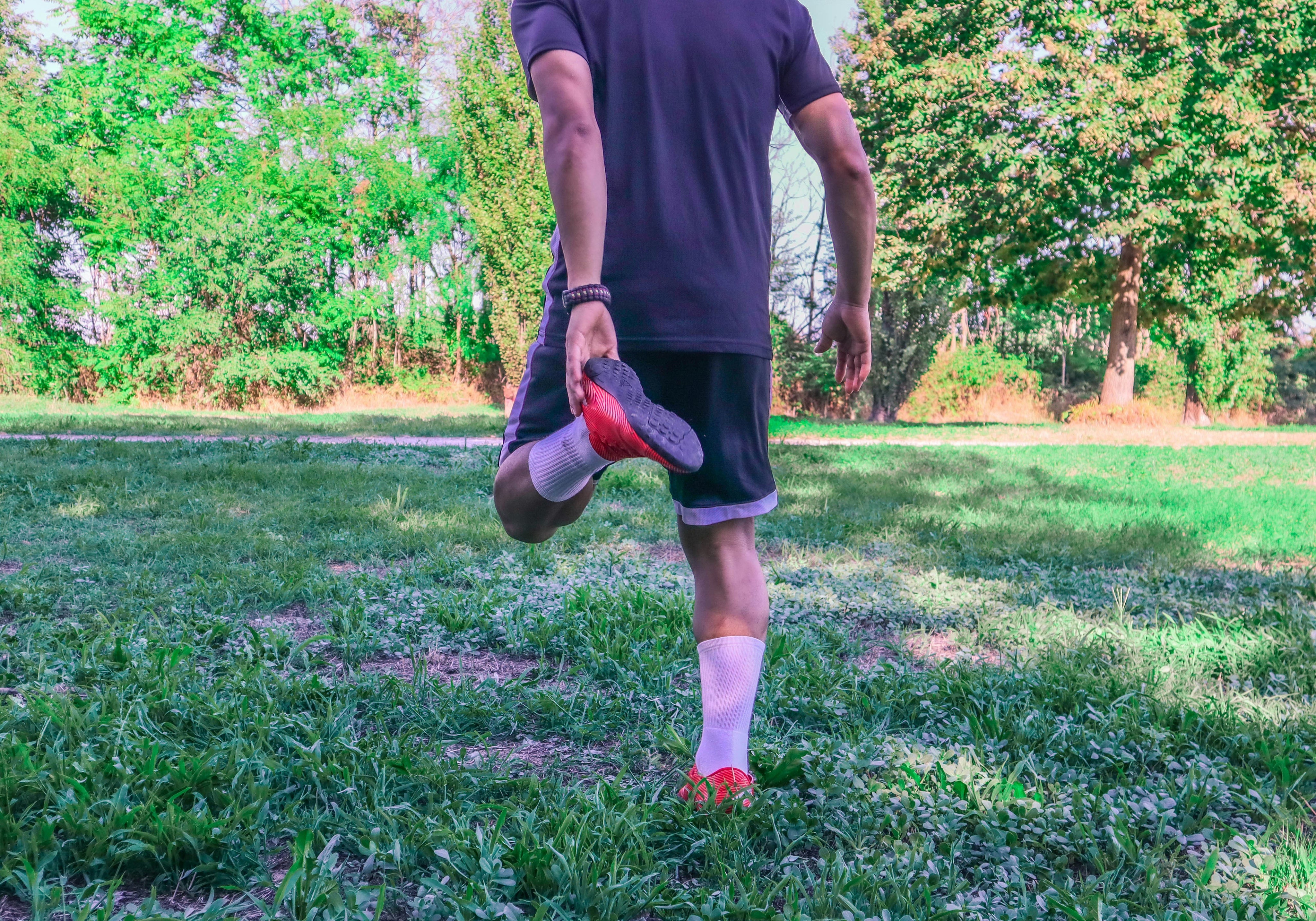 what helps sore muscles after workout? Man stretches post-workout in the grass