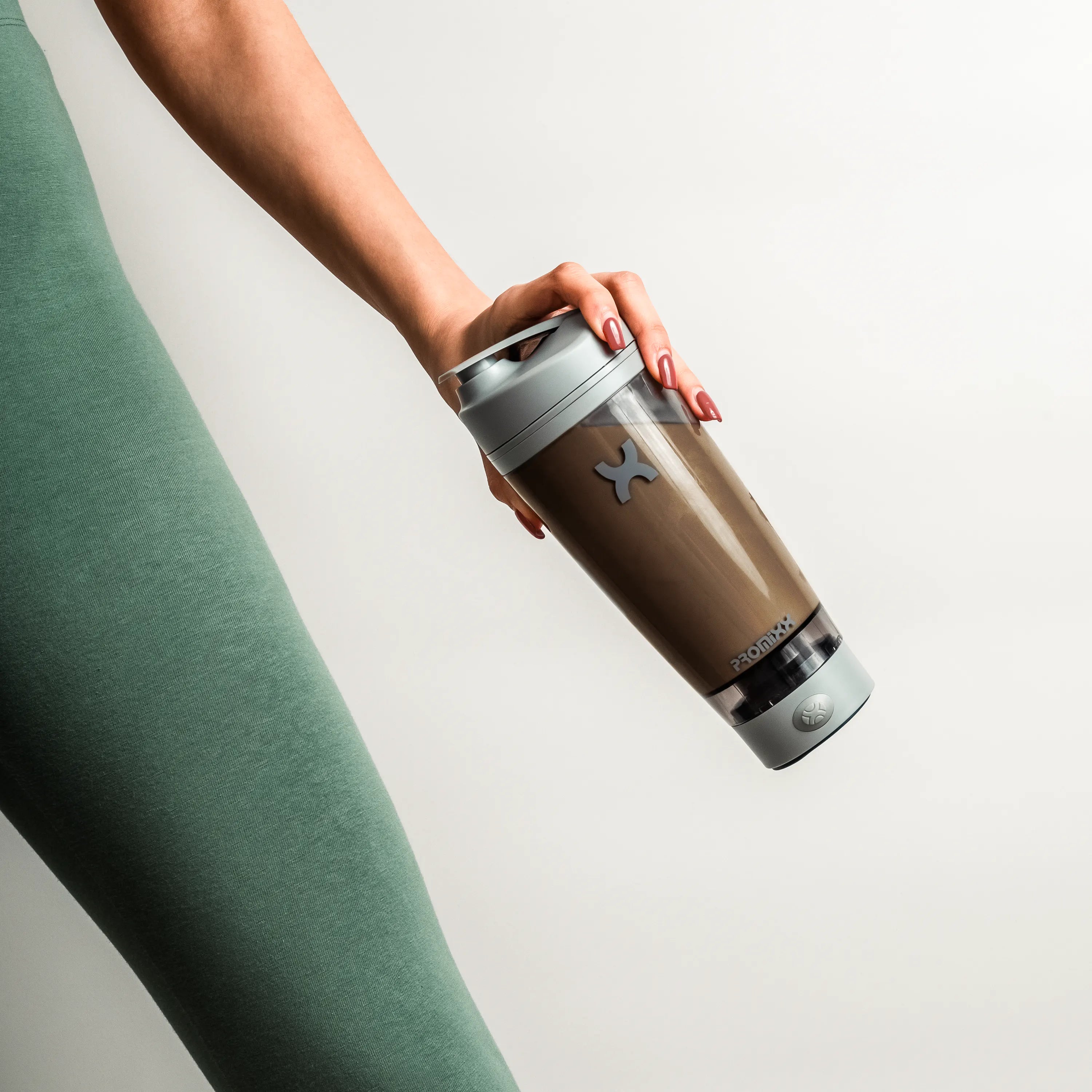 Person holding a brown insulated tumbler with a logo on a light gray background